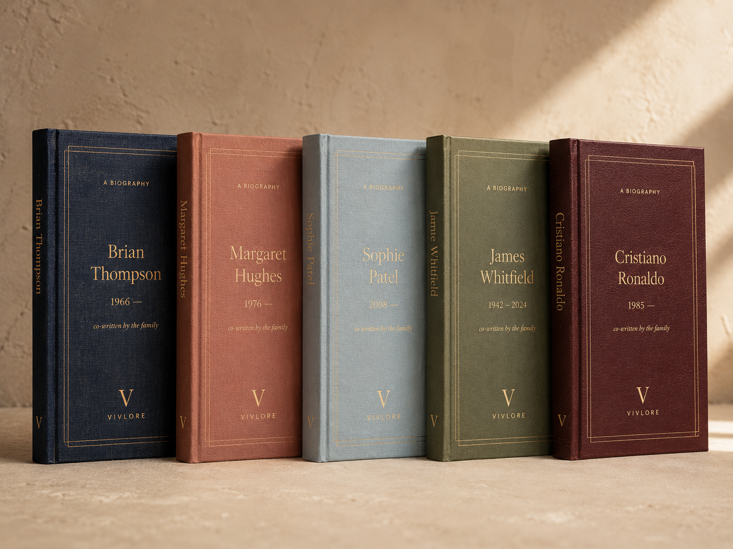 Five hardback Vivlore biographies on a beige photo-studio backdrop, Brian Thompson, Margaret Hughes, Sophie Patel, James Whitfield and Cristiano Ronaldo